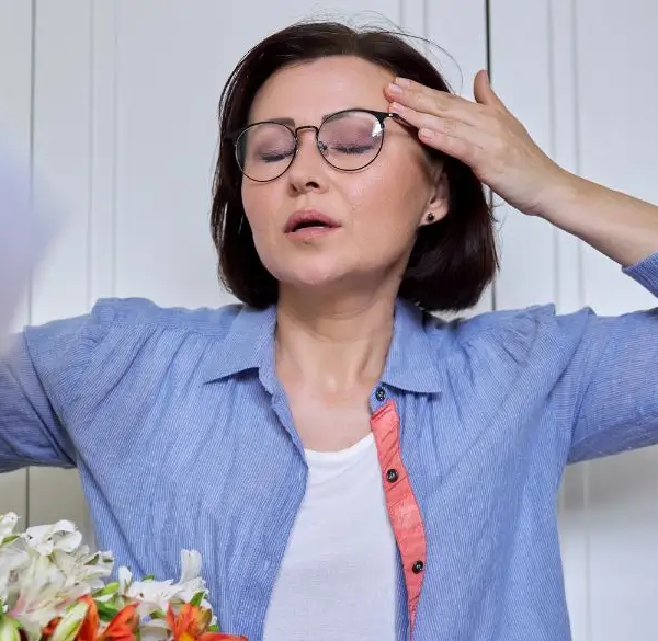 Woman having a hot flash, cooling herself with a paper