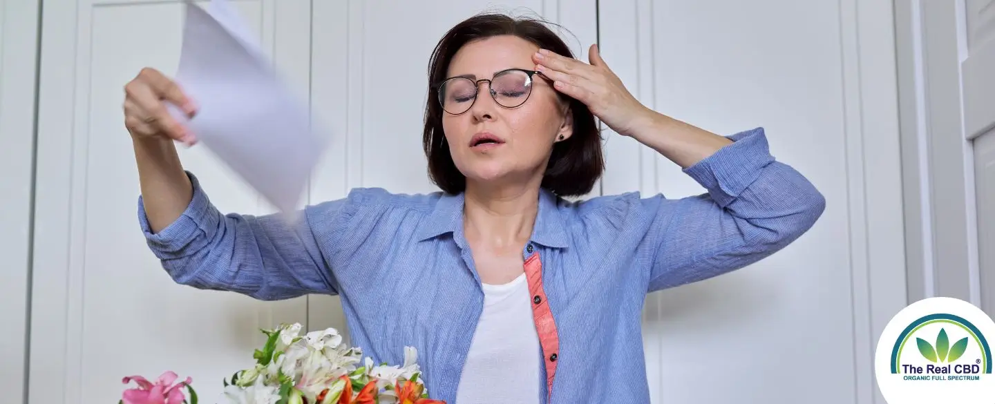 Woman having a hot flash, cooling herself with a paper