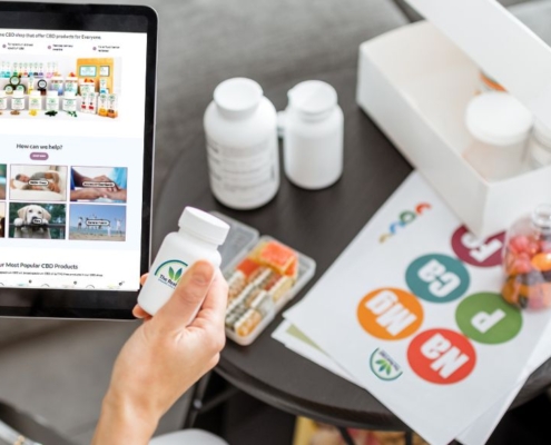 Man holding a tablet with The Real CBD website on and a jar of The Real CBD tablets