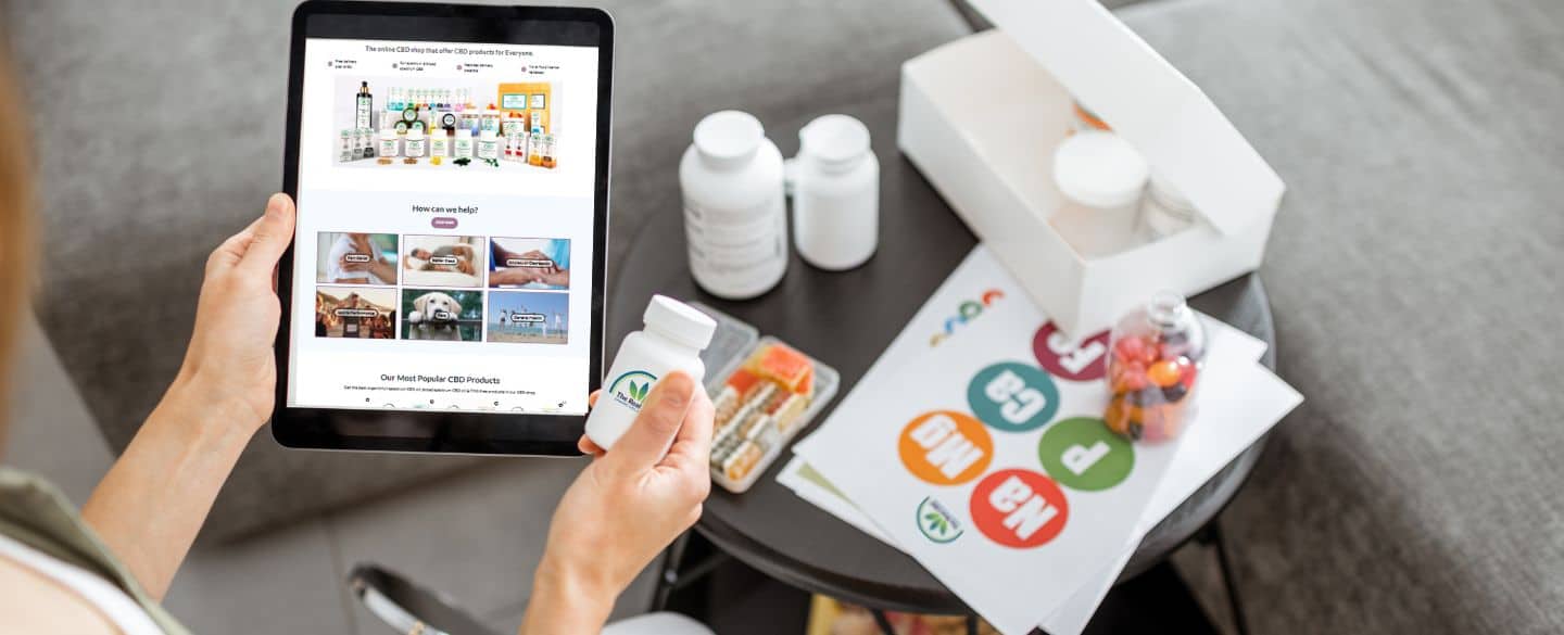 Man holding a tablet with The Real CBD website on and a jar of The Real CBD tablets