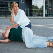 Woman calling for help for a person on the ground having a seizuer