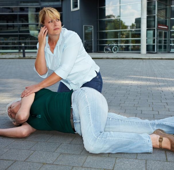 Woman calling for help for a person on the ground having a seizuer