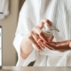 Woman in bathrobe squirting crème onto her hand